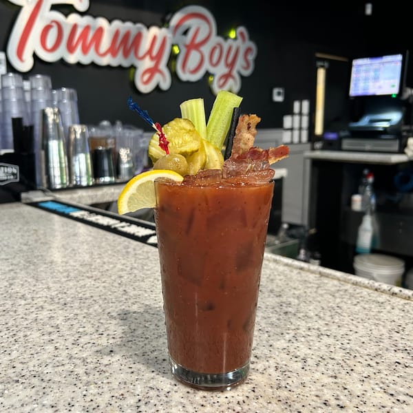 Bloody Mary cocktail with bacon, pickles, celery, and lemon on a bar counter at Tommy Boy's.